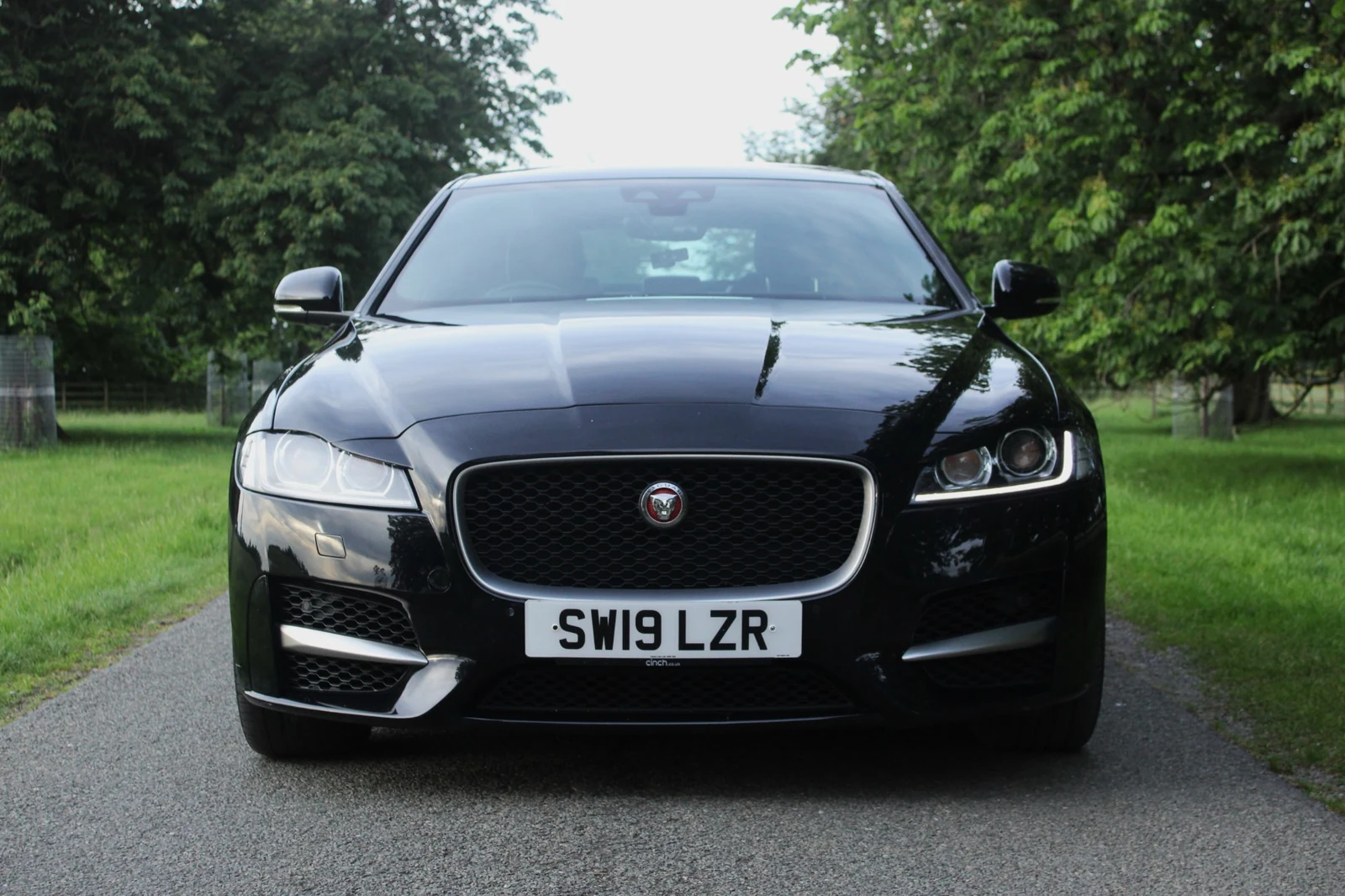 A straight front view of a black Jaguar showing its grille and headlights.