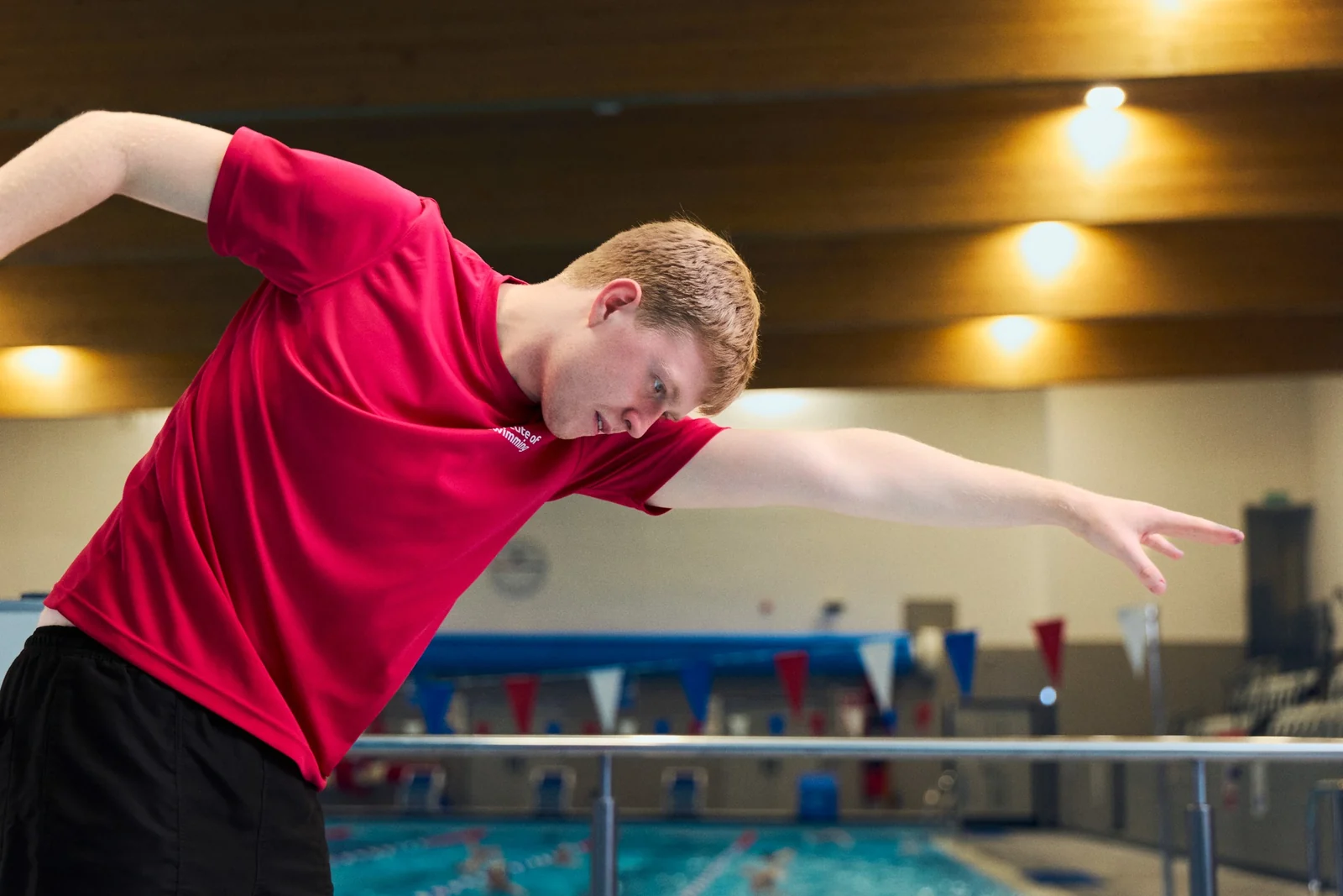 Jack Ruddle demonstrating a swimming movement beside the pool.